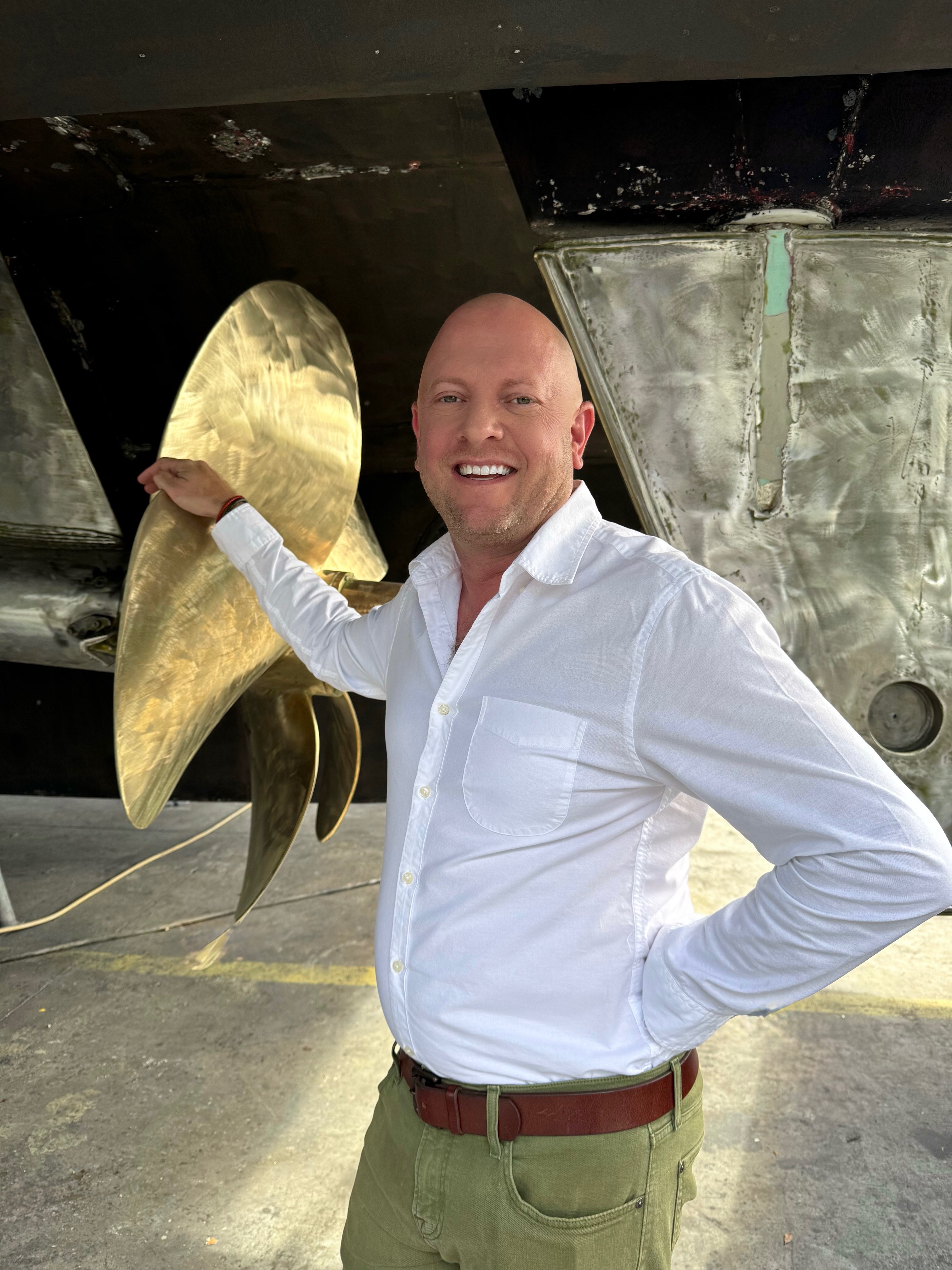 Smiling man holding a large gold leaf sculpture in an industrial space