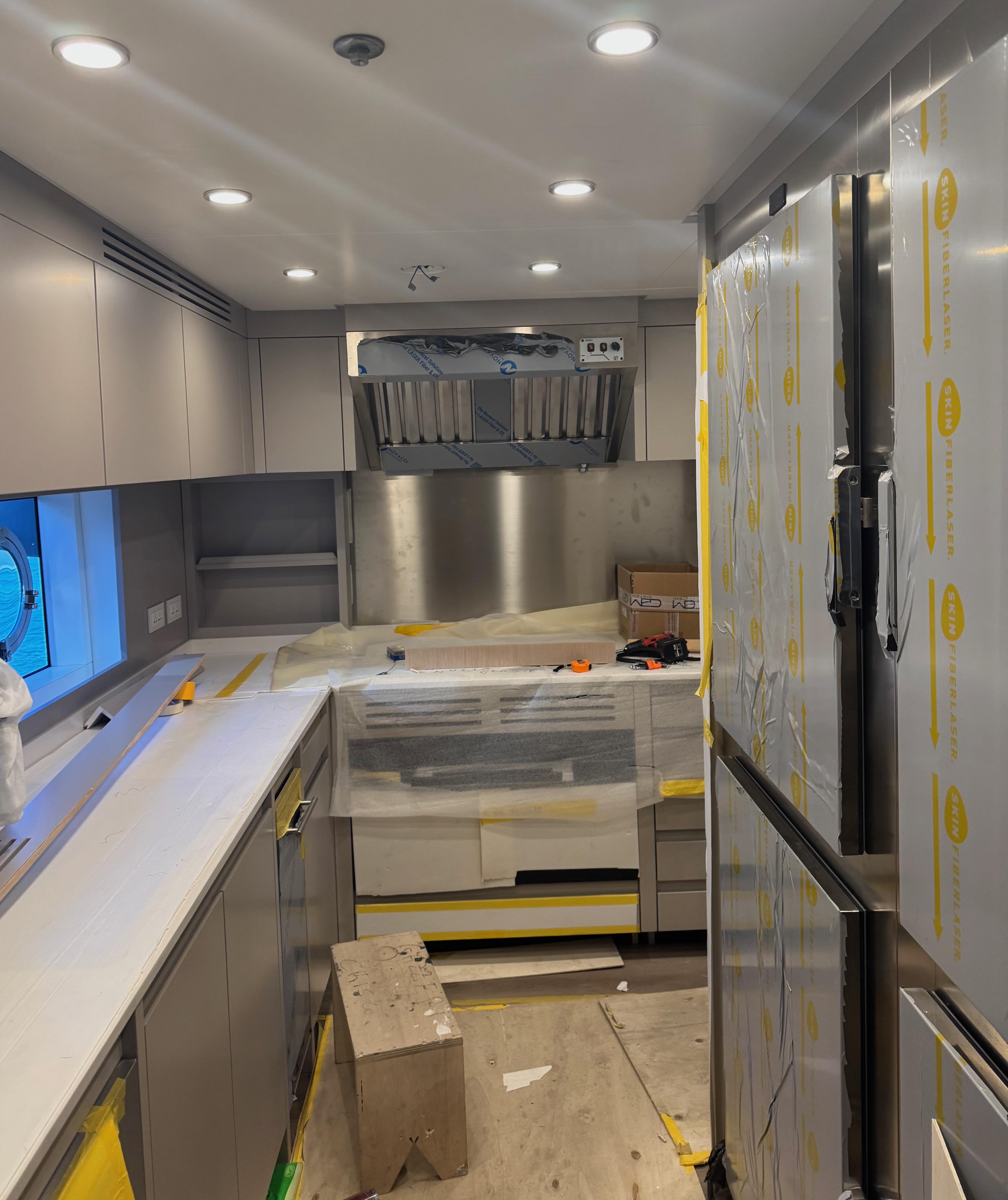 Partially finished galley with cabinets, countertops, and wrapped appliances under construction